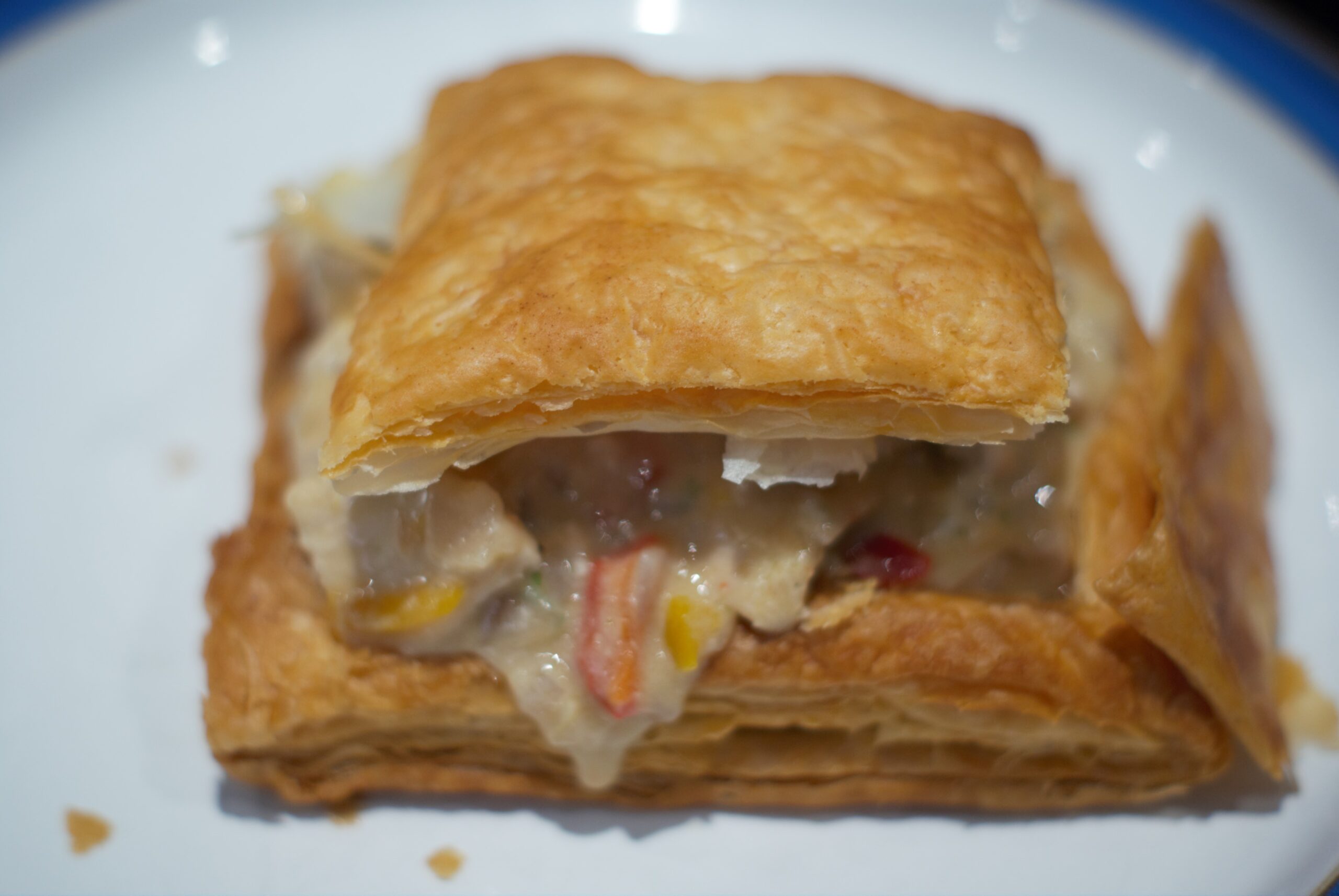 Creamy chicken filling falling out of a puff pastry pie